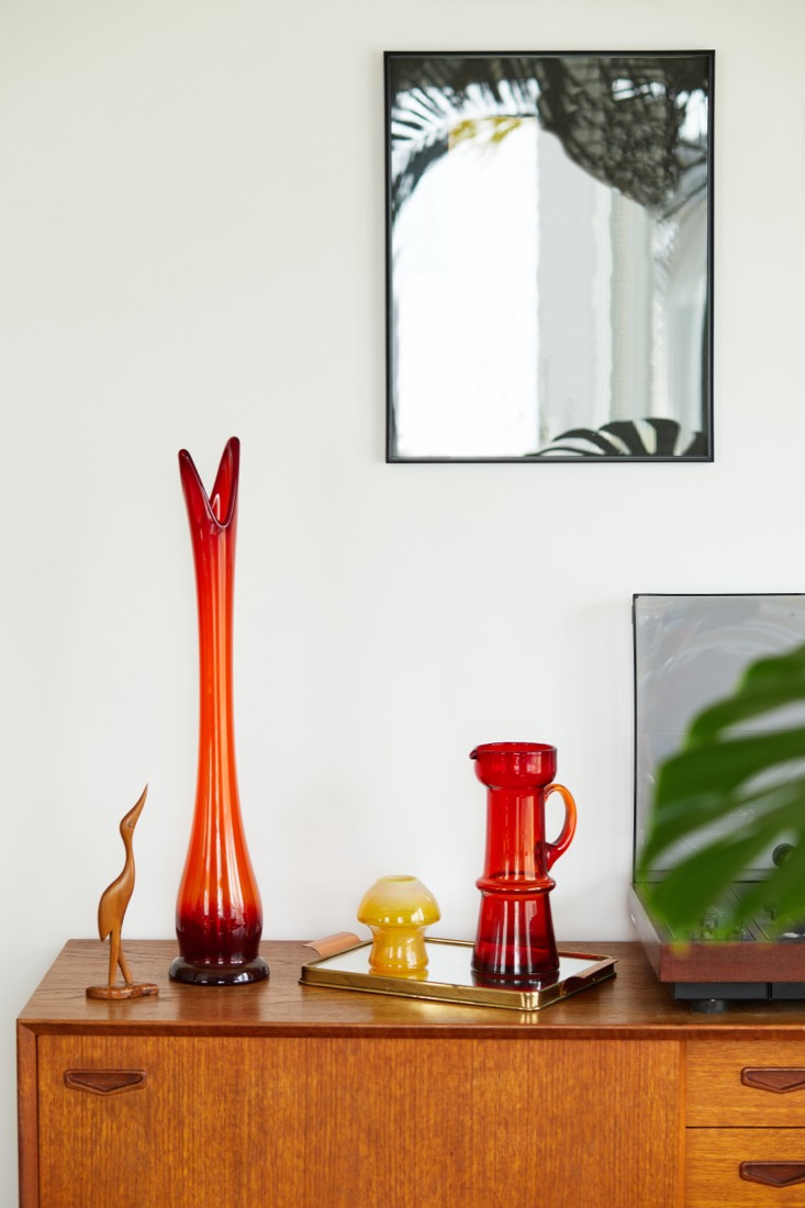 A small yellow mushroom lamp glowing beside red vintage glassware on a brass tray.