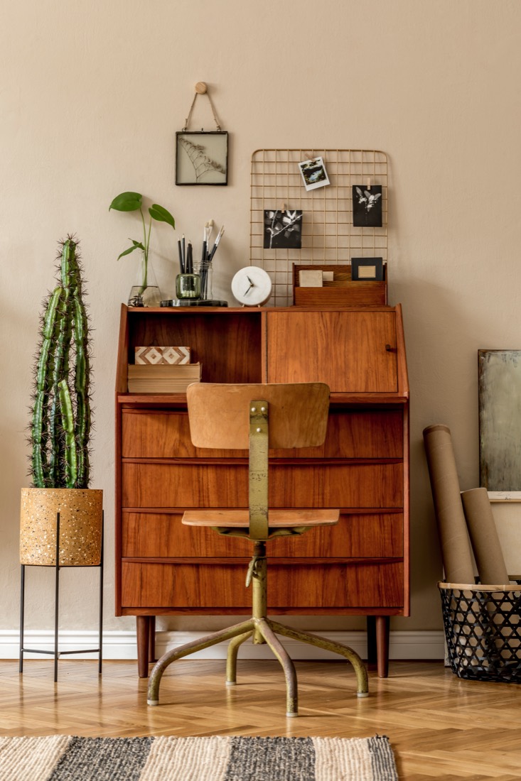 A teak cabinet lit low and warm, with a cork planter and a cactus.